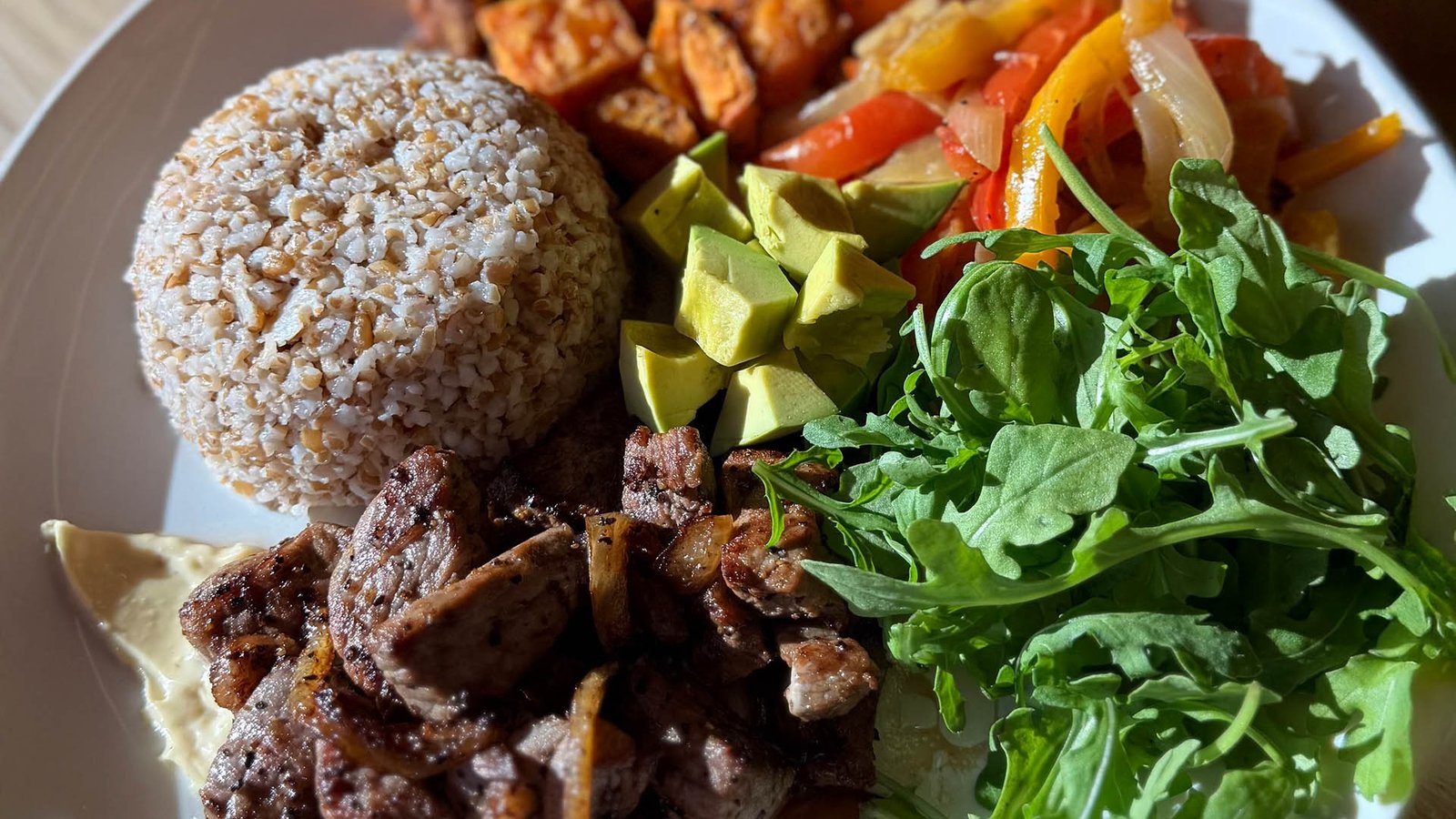 Pan-seared steak with five grains, avocado and arugula